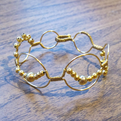 Bead wrapped wire bracelet with matching metal beads, goldtone
